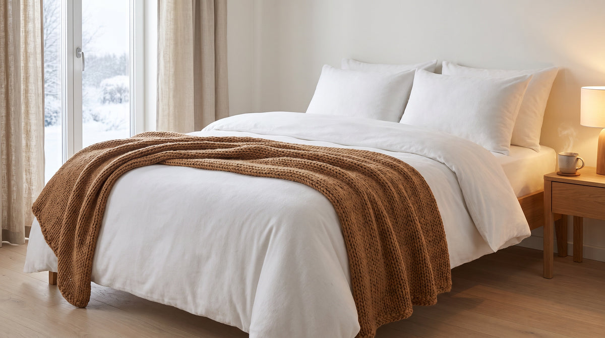 Winterliches Schlafzimmer mit weißer Biber-Bettwäsche und Strickdecke